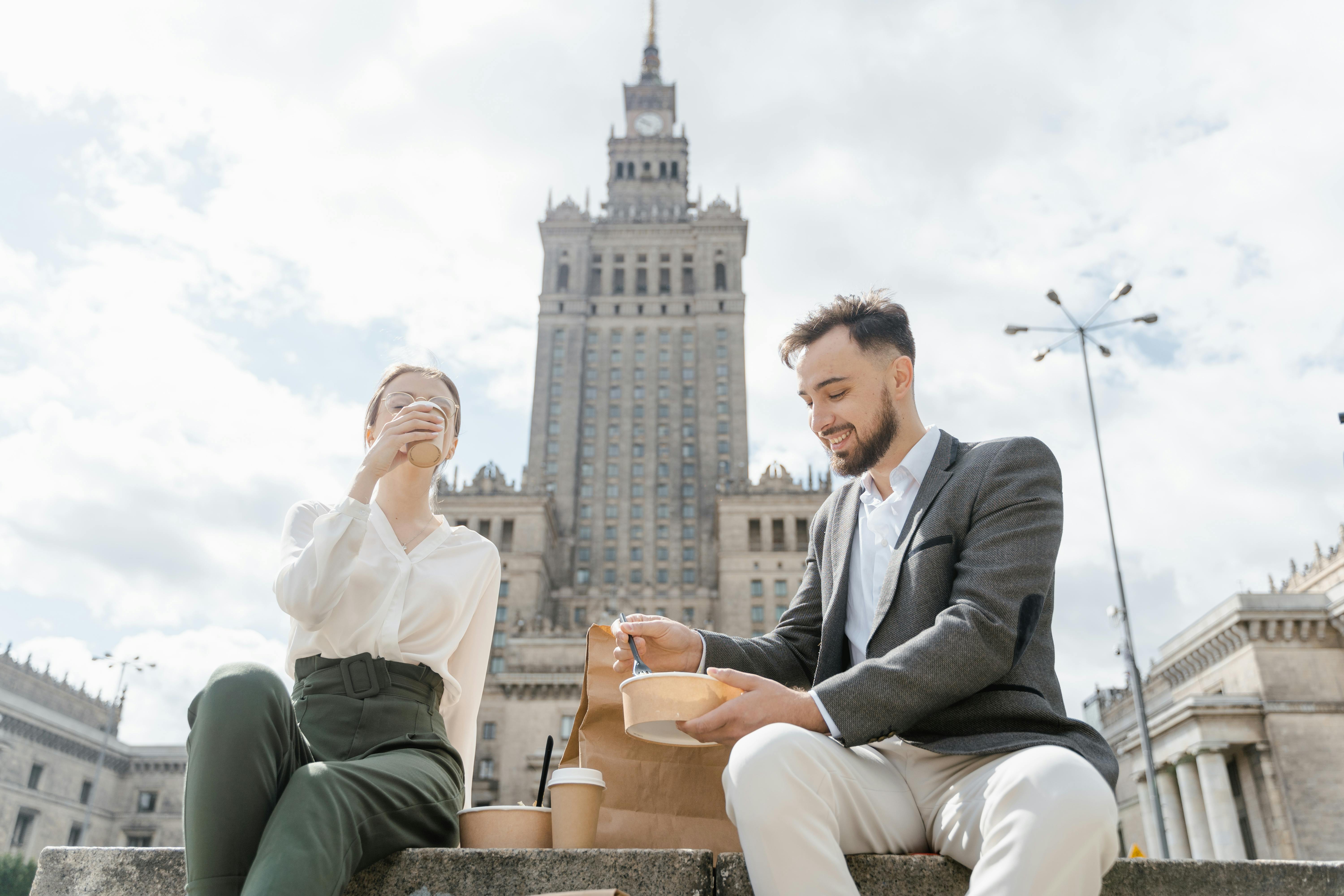 man and woman having coffee beside a high rise building