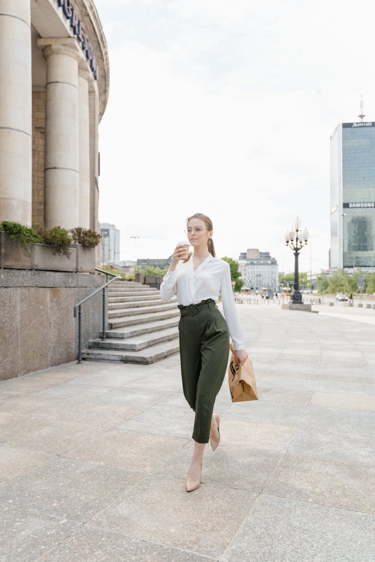 A Woman In Whit Long Sleeves Holding A Brown Paper Bag 