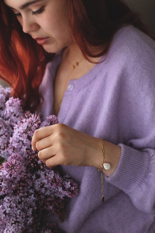 A Woman in Purple Knit Sweater Holding Purple Flowers