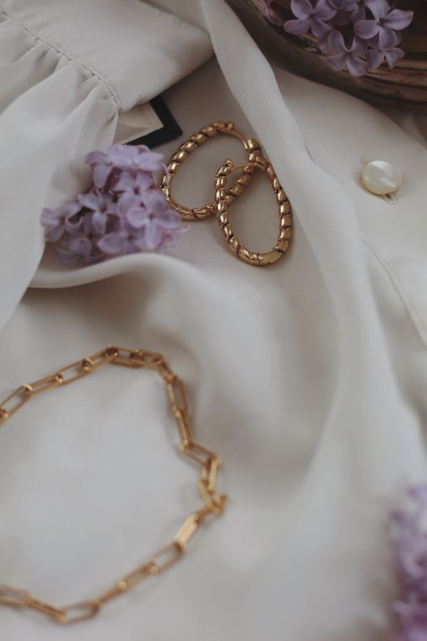 Gold jewellery laid on light fabric — photo by Ioana Motoc on Pexels