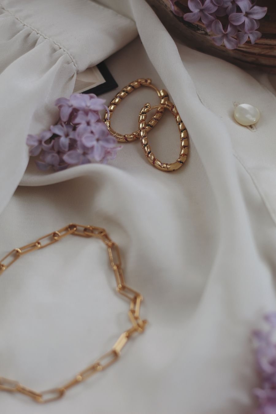 Gold jewelry on light fabric with purple flowers
