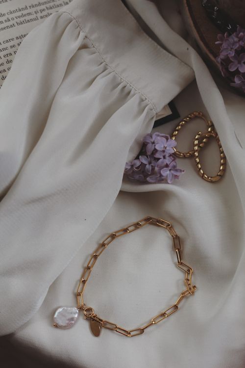 Free Stunning flat lay of gold jewelry with lilac flowers on elegant fabric. Perfect for fashion and lifestyle themes. Stock Photo