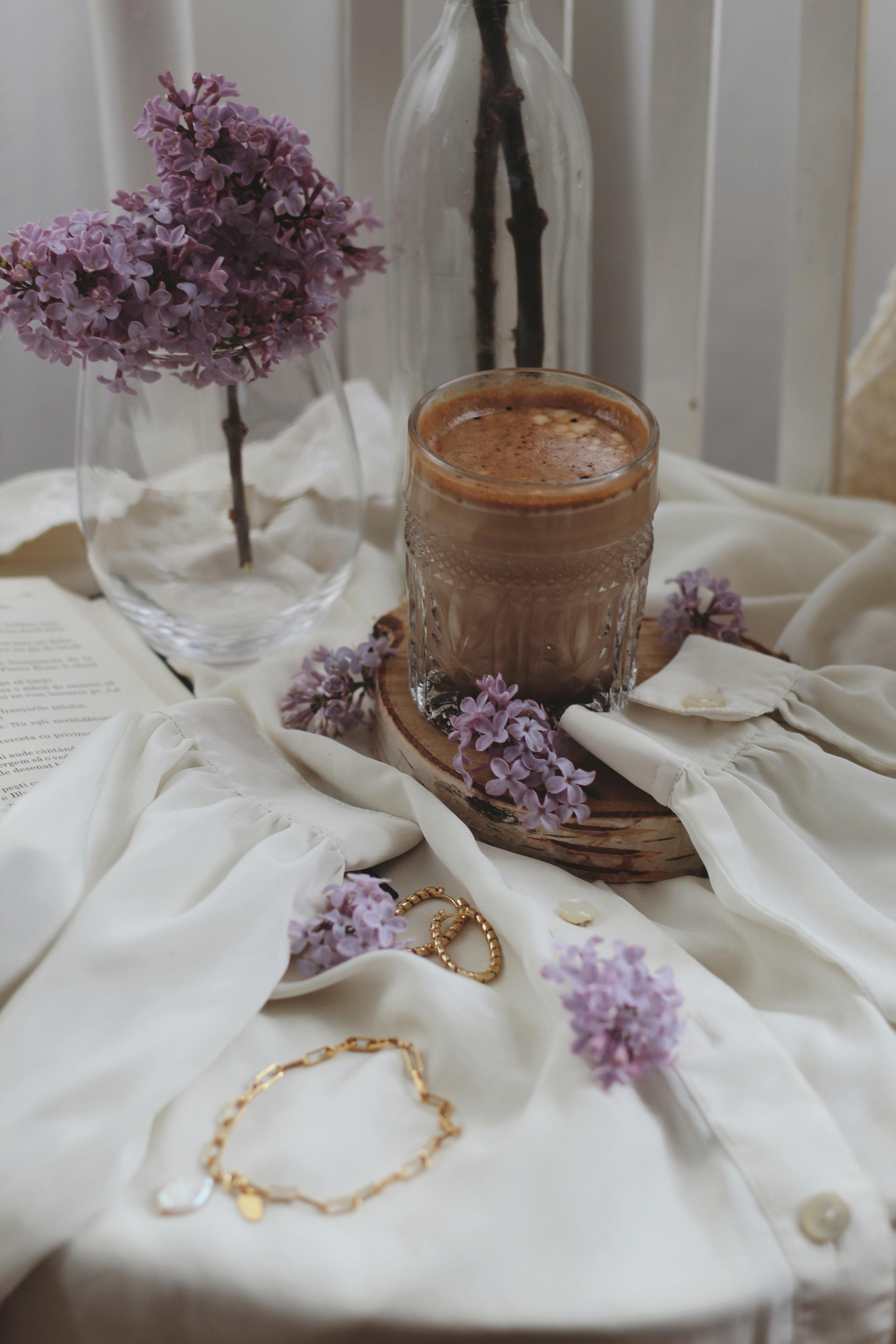 Free A warm scene of a chocolate drink surrounded by lilacs on a white blouse. Stock Photo