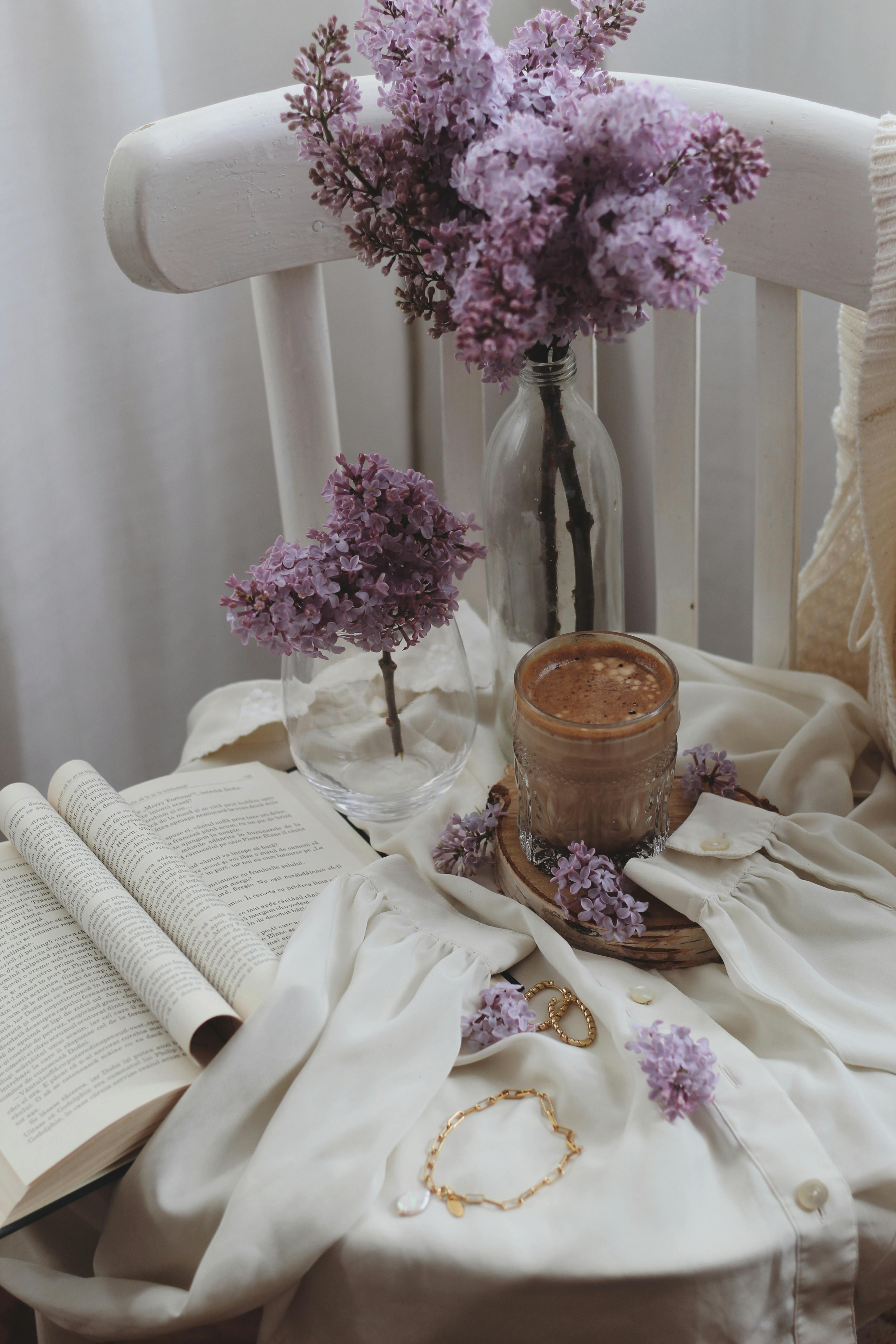 Free A warm scene of coffee, lilacs, and a book for a cozy indoor ambiance. Stock Photo
