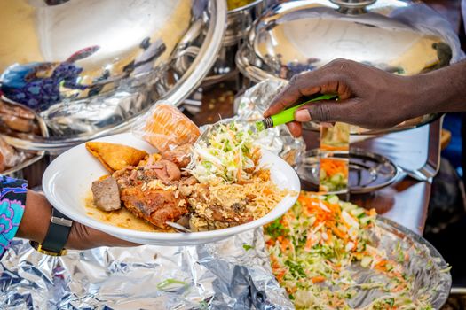 A vibrant plate of Nigerian cuisine being served at a buffet, showcasing local delicacies.