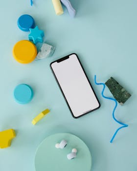 A smartphone on a pastel blue surface with colorful elements, ideal for technology mockups.