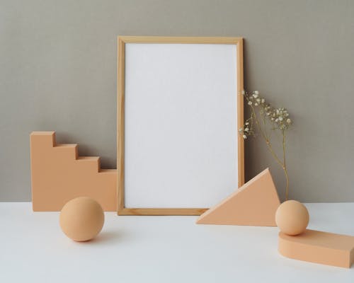 

A Blank Wooden Frame and Shapes on a White Surface