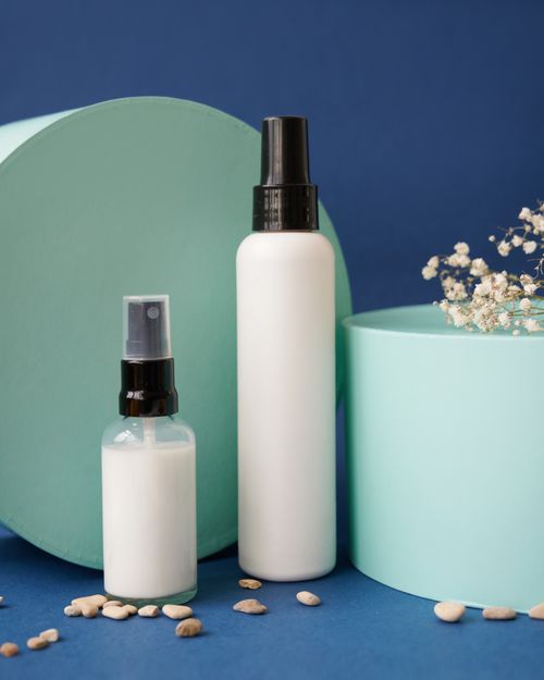Free Two spray bottles on a textured surface, styled with round containers and pebbles. Stock Photo