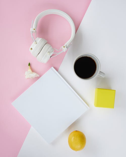 A Book beside a Cup of Coffee and Headphones