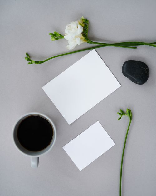 Free Minimalist flat lay with coffee, flowers, stones, and blank cards on a gray background. Stock Photo