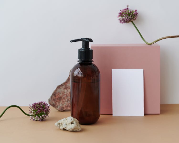 Brown Glass Container, Flowers And A Blank Paper Sheet 