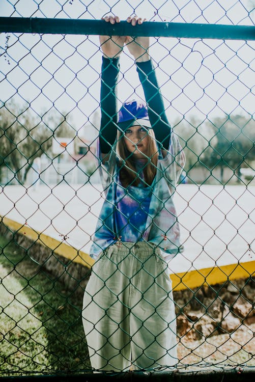 Woman Hanging on to the Wire Mesh Fence Wearing Sports Attire