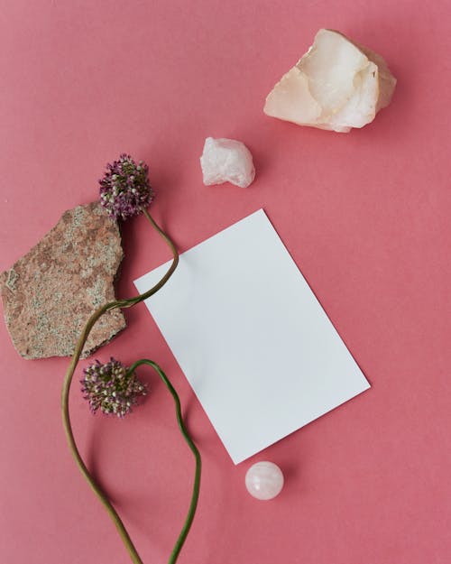 Blank Sheet of Paper on Pink Background Surrounded by Rock Chunks