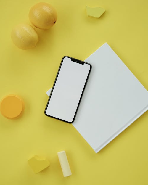 Blank Paper Sheet and a Smartphone with a White Blank Display 