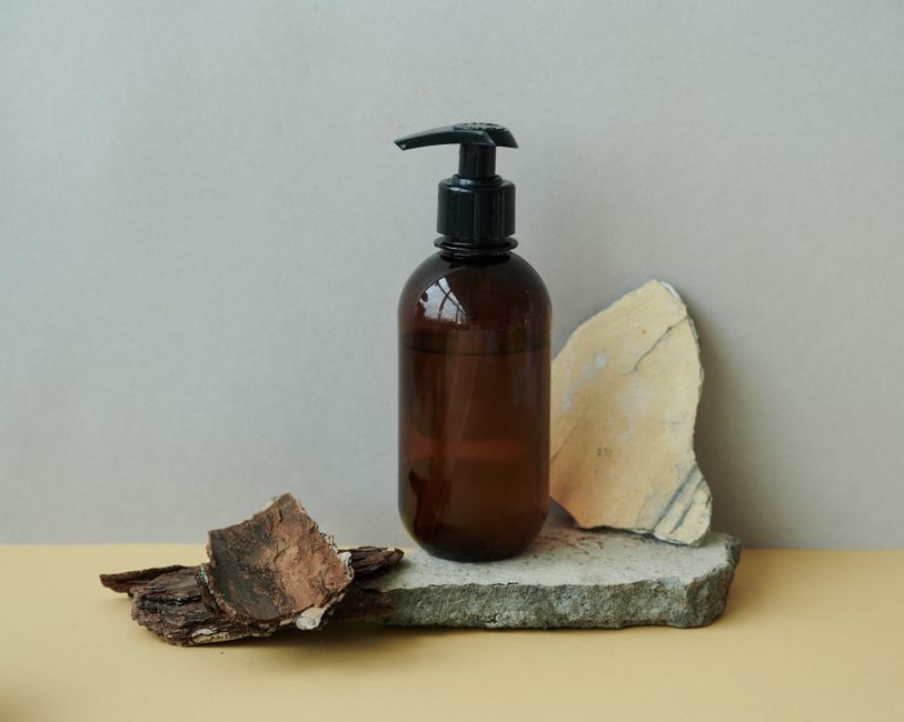 Brown pump bottle on stone and wood, highlighting eco-conscious packaging.