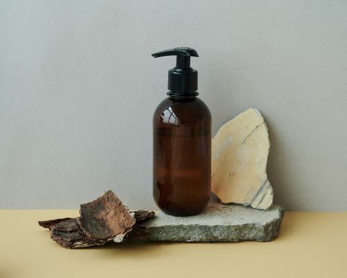 Free Brown pump bottle on stone and wood, highlighting eco-conscious packaging. Stock Photo