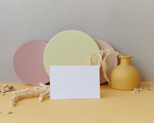 Free Minimalist scene with blank card, colorful circles, vase, and textured background. Stock Photo