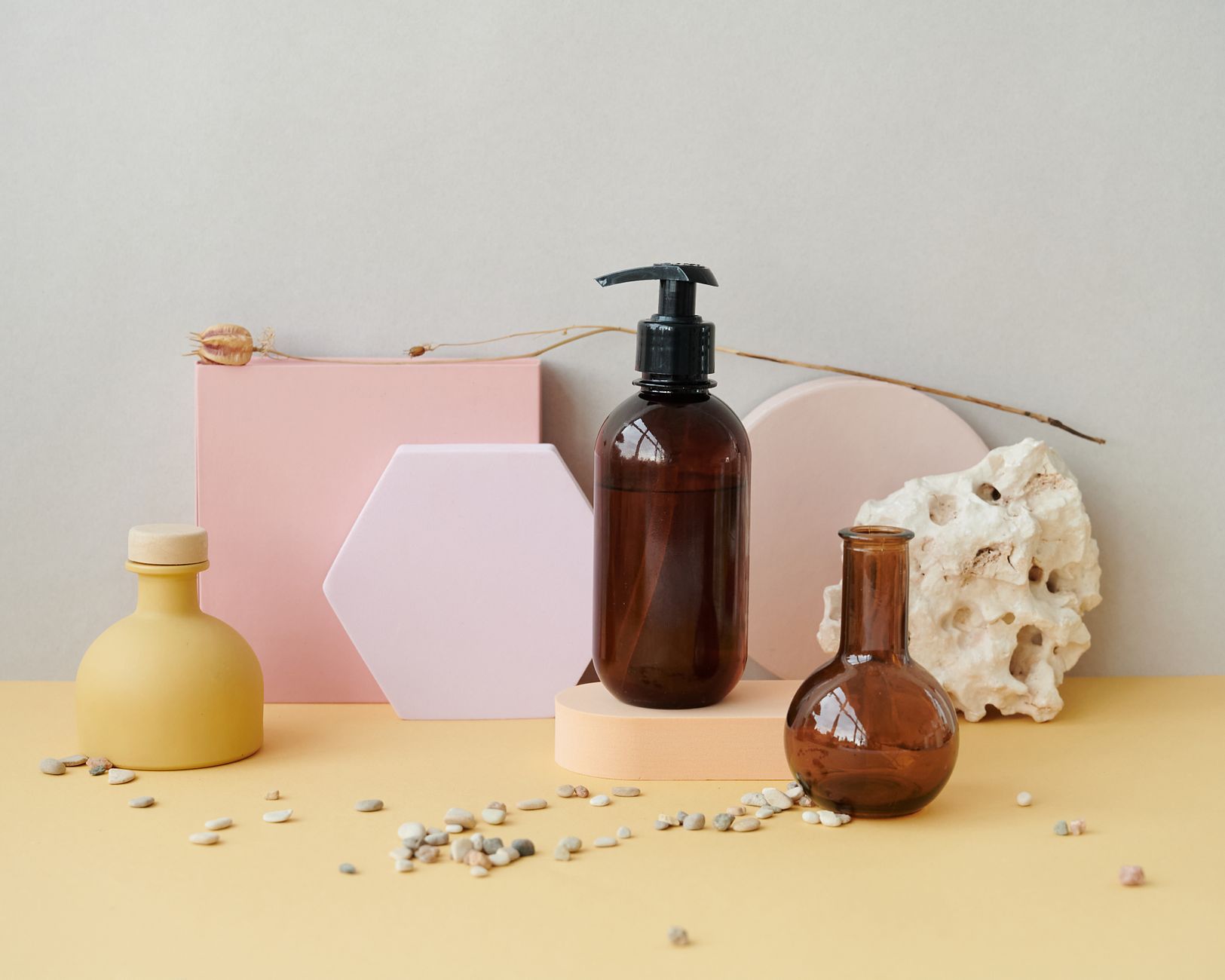Aesthetic composition of bottles with pastel geometric shapes and pebbles, perfect for product display.