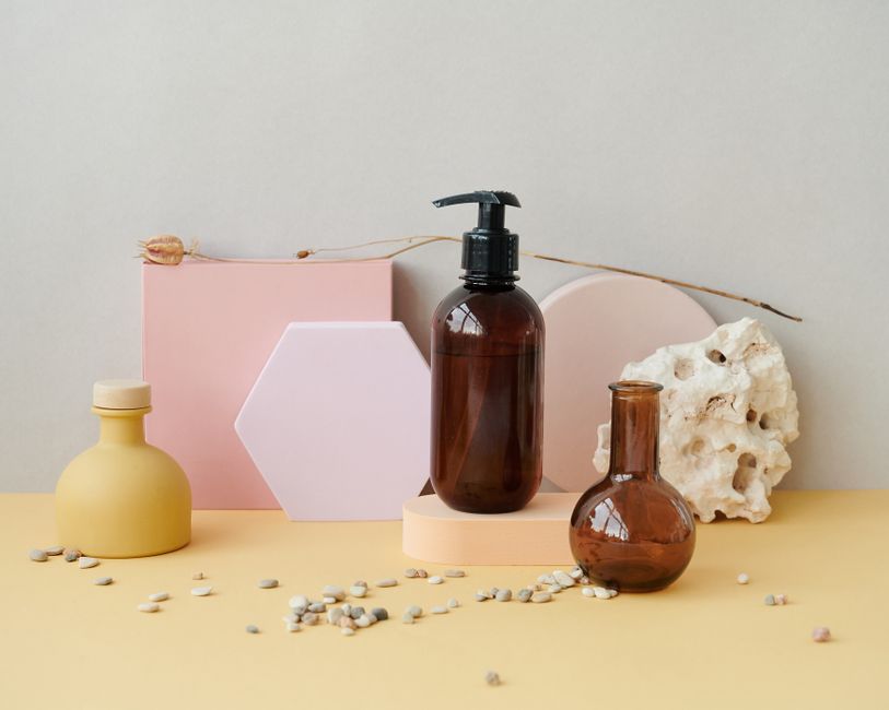 Aesthetic composition of bottles with pastel geometric shapes and pebbles, perfect for product display.