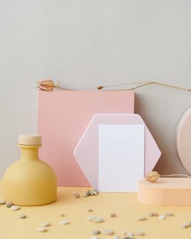 A minimalist arrangement with geometric shapes and a blank card on a pastel background.