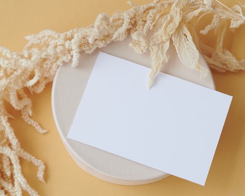 Free Minimalistic flat lay featuring a blank card, dried grass, and a round base on a warm background. Stock Photo