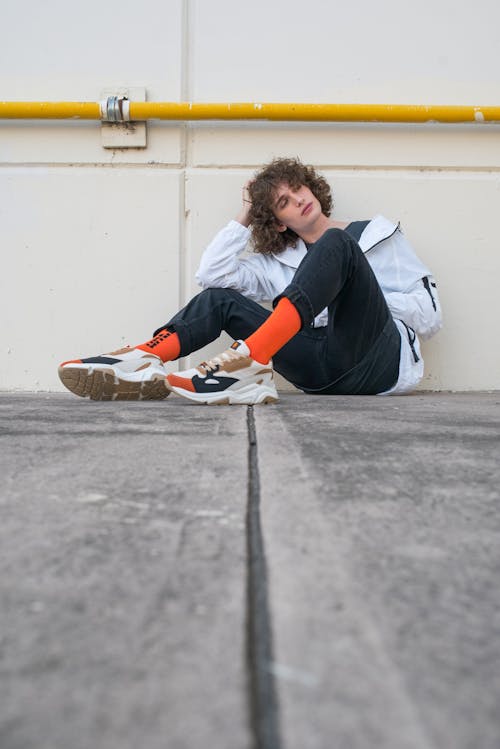 A Man Wearing a Jacket and Orange Socks Sitting on the Floor
