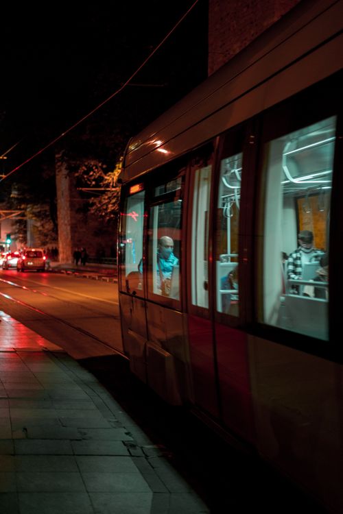 Free Moody city street scene featuring a tram with passengers traveling at night. Stock Photo