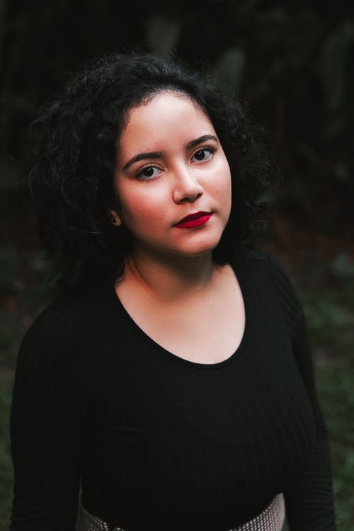 Free Portrait of a woman with curly hair and red lips in an outdoor setting. Striking and elegant expression. Stock Photo
