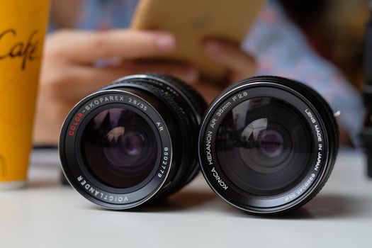 Close-up image of two camera lenses on a table in a café, emphasizing photography equipment.