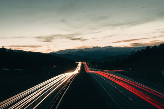 Captivating long exposure of highway light trails under Colorado's twilight sky, featuring distant mountains.