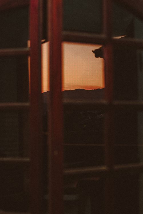 Free A serene sunset view through a balcony door with silhouetted details. Stock Photo