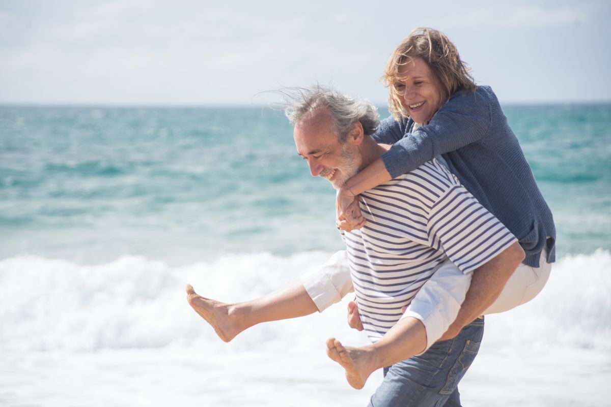 Happy senior couple walking together along a sunny beach
