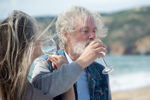 Pasangan matang santai minum wain di pantai