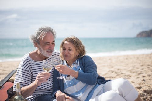 คู่รักสูงวัยจิบไวน์บนชายหาดโรแมนติก