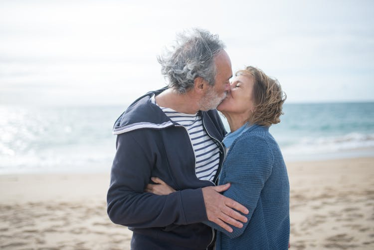 An Elderly Couple Kissing At The Beach