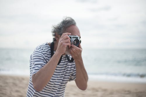 Gray Haired Person Taking Photo Using a Silver and Black Camera