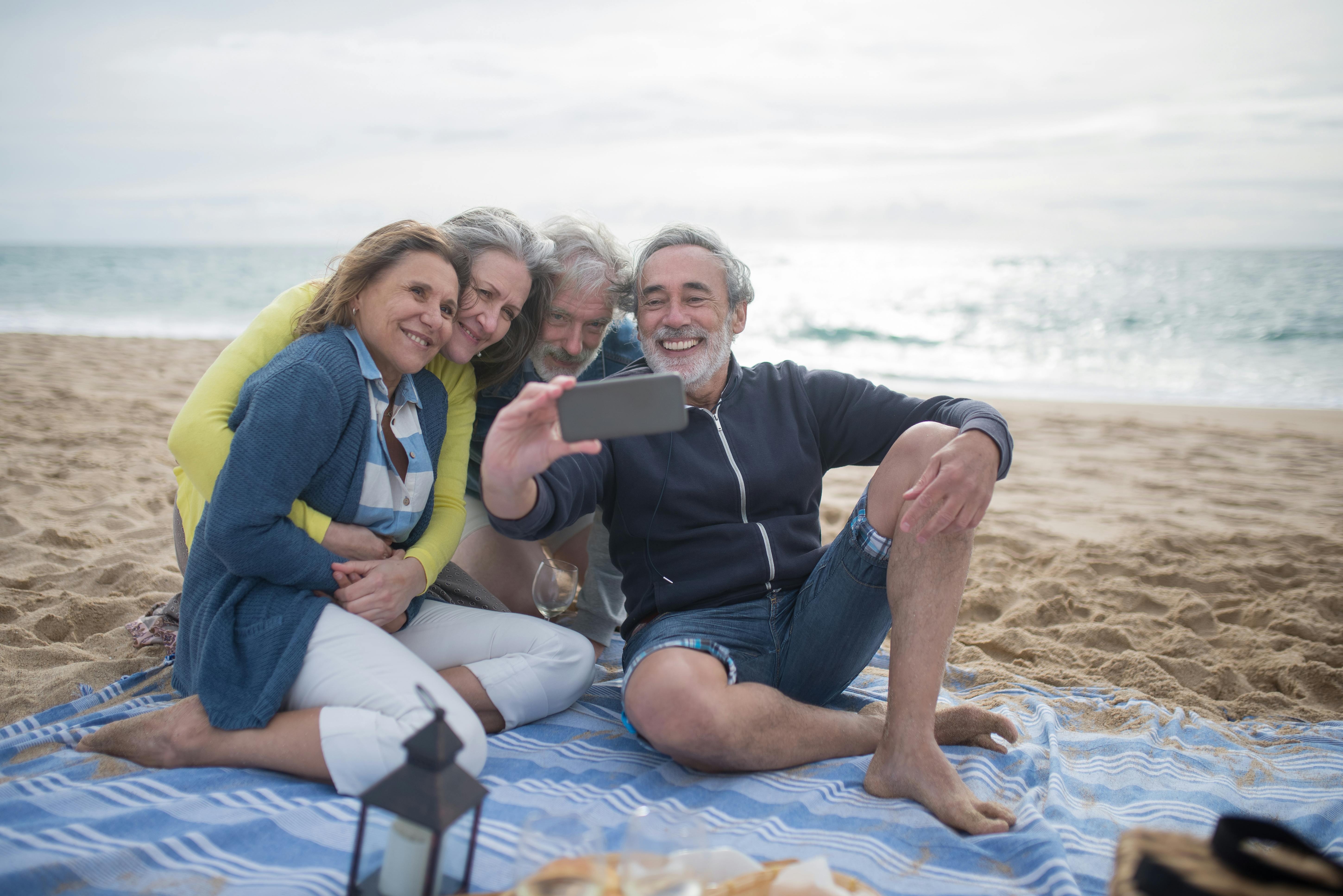 people taking photos while sitting on picnic blanket