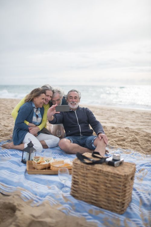 Free A joyful group of seniors taking a selfie during a beach picnic in Portugal. Stock Photo