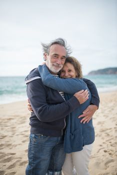 Happy senior couple embracing on a picturesque beach in Portugal, showcasing love and joy.