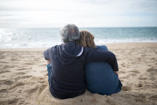 Free A senior couple hugging and relaxing on a sandy beach in Portugal. Stock Photo