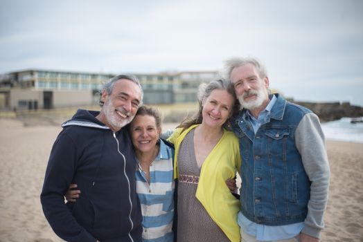 A cheerful group of mature friends enjoying a day at the beach in Portugal, showcasing togetherness.