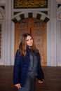 Woman in Blue Jacket Standing Near the Brown Wooden Door