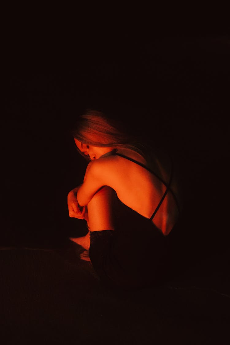 Woman In The Dark Hugging Her Knees