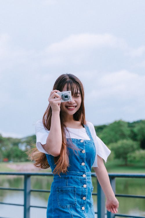 Free Woman in Blue Denim Dungaree Taking Photos Using a Camera Stock Photo