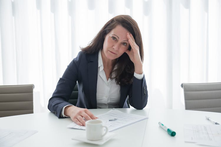 Woman In Corporate Attire With Hand On Head