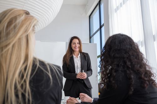 Free Three professional women engaged in a business meeting, discussing a project in a modern office setting. Stock Photo
