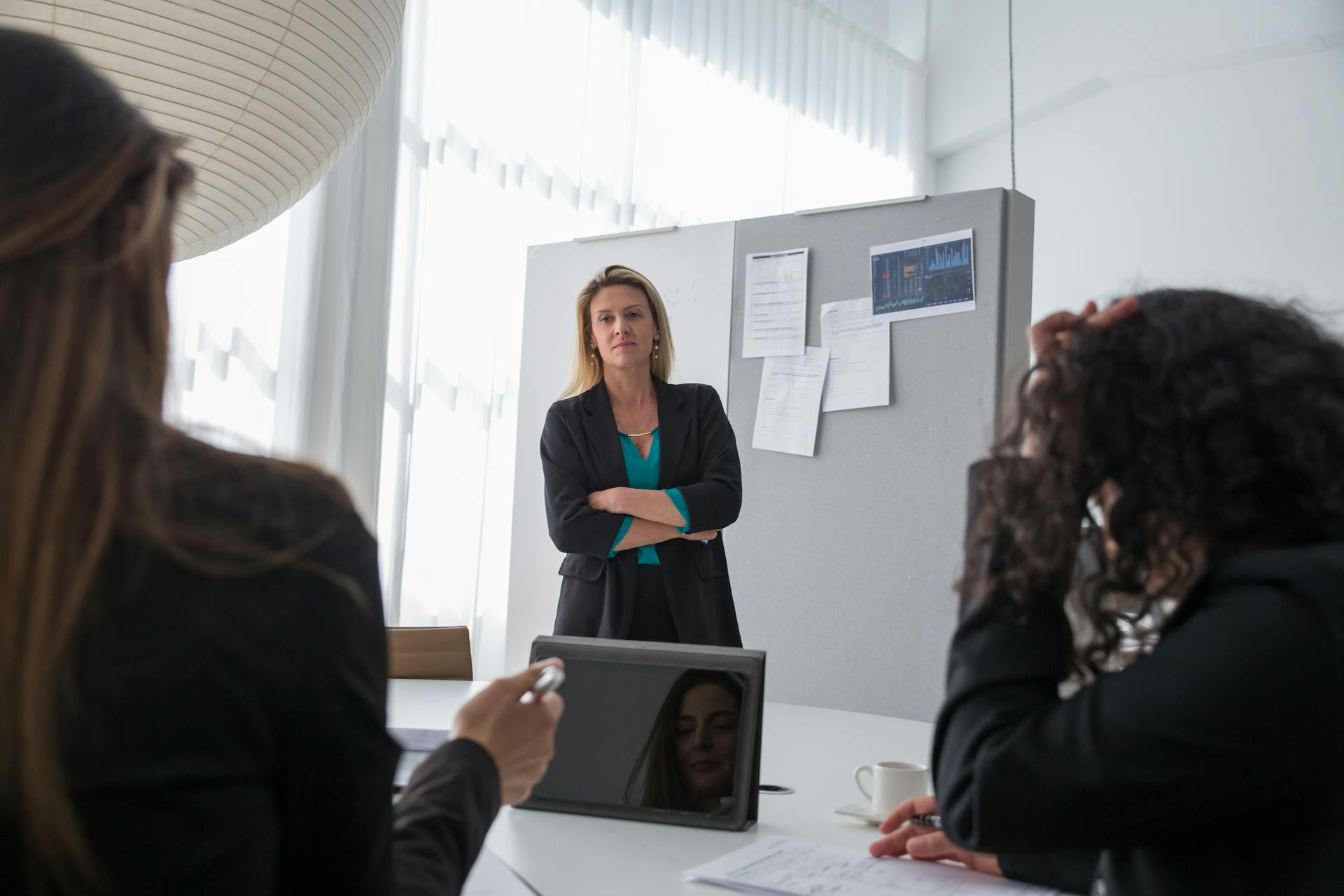 Professional woman presenting at a corporate meeting with colleagues in office environment.