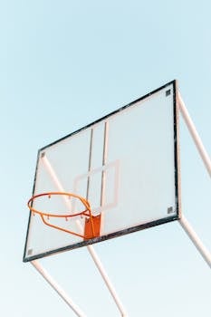 Minimalist photo of a basketball hoop and backboard against a clear sky. Perfect for sports themes.