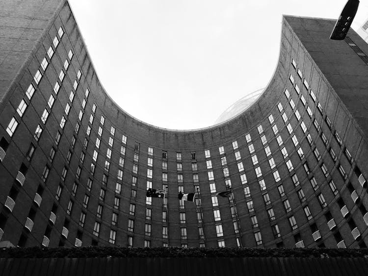 A Curved Building With Flag Poles