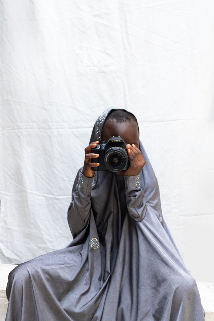 Photo Of A Kid In Traditional Clothes Holding A Black Camera